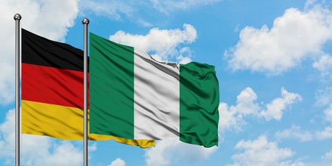 Germany and Nigeria flag waving in the wind against white cloudy blue sky together. Diplomacy...