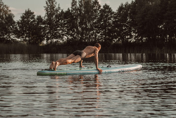 A young guy makes a plank on a sup Board. SUP yoga,