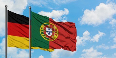 Germany and Portugal flag waving in the wind against white cloudy blue sky together. Diplomacy...