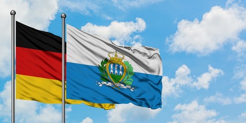 Germany and San Marino flag waving in the wind against white cloudy blue sky together. Diplomacy concept, international relations.