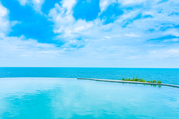 Fototapeta na wymiar Beautiful outdoor infinity swimming pool in hotel resort with sea ocean view and white cloud blue sky