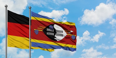 Germany and Swaziland flag waving in the wind against white cloudy blue sky together. Diplomacy...