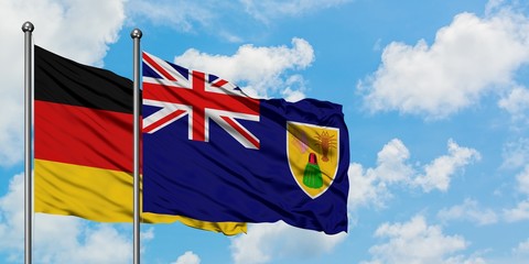 Germany and Turks And Caicos Islands flag waving in the wind against white cloudy blue sky together. Diplomacy concept, international relations.