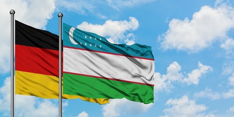 Germany and Uzbekistan flag waving in the wind against white cloudy blue sky together. Diplomacy concept, international relations.