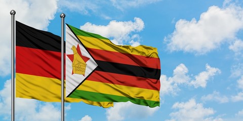 Germany and Zimbabwe flag waving in the wind against white cloudy blue sky together. Diplomacy concept, international relations.