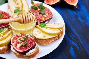 Bruschetta and Crostini with pear, ricotta cheese, honey, figs, nuts and herbs. Breakfast toasts or snack sandwiches. Antipasto. Italian food. Top view. Copy space.