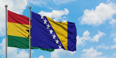 Ghana and Bosnia Herzegovina flag waving in the wind against white cloudy blue sky together....