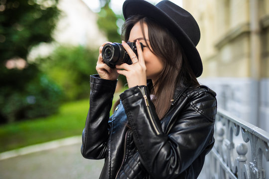 Young pretty asian girl making pictures with her camera in the street