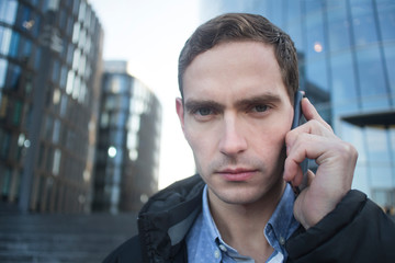 Serious morose moody guy, businessman talking on his cell mobile phone and looking at camera, close...