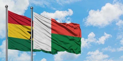 Ghana and Madagascar flag waving in the wind against white cloudy blue sky together. Diplomacy...