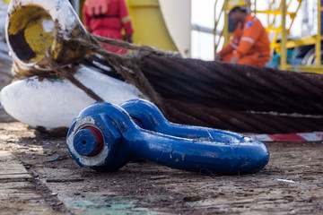 Blue painted shackle for lifting tackle color coding laid on deck of a construction barge at oil...