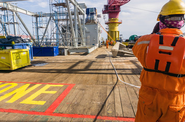 Offshore rigger or roughneck preparing rigging for tugger rope on deck of a construction barge at...