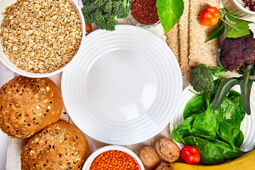 Selection food rich in fiber on white wooden background around empty plate, Healthy diet food product. Top view, flat lay, copy space..