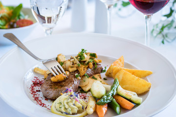 Lende mit Pilzen, Kartoffelspalten, Gemüse und Kräuterbutter