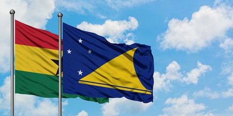 Ghana and Tokelau flag waving in the wind against white cloudy blue sky together. Diplomacy...