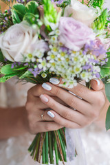 Fototapeta premium Beautiful trendy stylish manicure of bride. Woman holding pastel flowers bouquet. Vertical color photography.