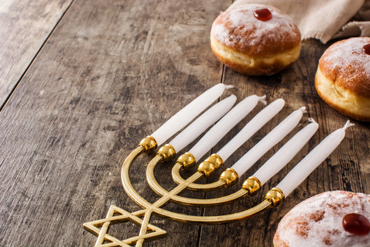 Jewish Hanukkah menorah and sufganiyot donuts on wooden table. Copy space	