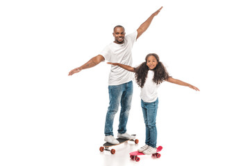happy african american father and daughter balancing on longboard and skate on white background