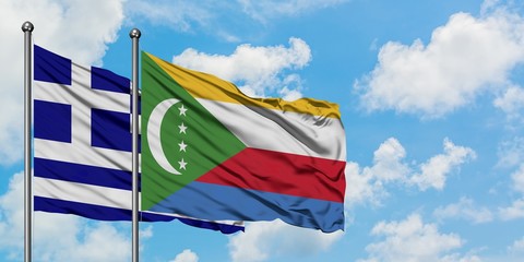 Greece and Comoros flag waving in the wind against white cloudy blue sky together. Diplomacy...