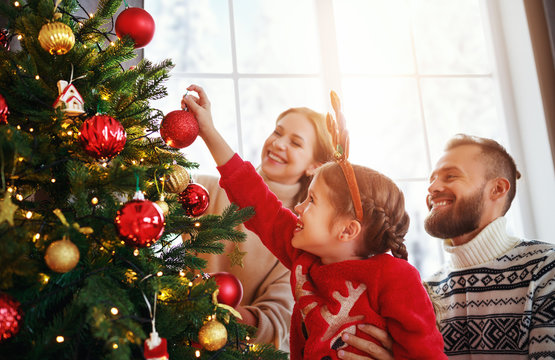 happy family mother, father and child daughter decorate Christmas tree  .