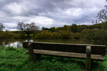 Fototapeta premium Alte Holzbank am Fluss in Lahnau im Herbst