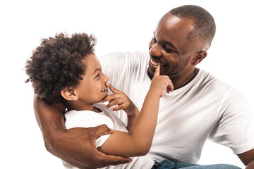 cheerful african american boy touching own nose and nose of happy father isolated on white