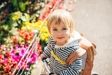 Outdoor portrait of a cute little toddler girl, riding a bike, wearing backpack