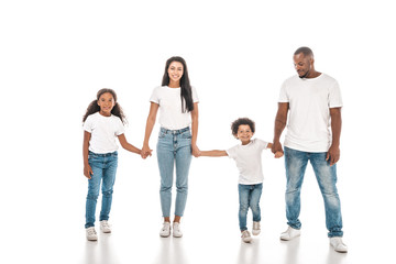 Obraz premium happy african american mother, father, daughter and son holding hands and smiling on white background