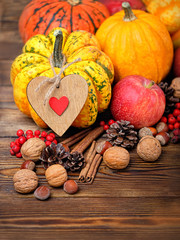 autumn Thanksgiving concept. Fall pumpkin arrangement. pumpkins, apples, berries on rustic wooden background. pumpkins with heart decor on table. copy space