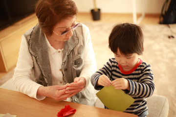 折り紙で遊ぶシニア女性と男の子