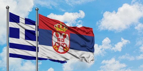 Greece and Serbia flag waving in the wind against white cloudy blue sky together. Diplomacy concept, international relations.