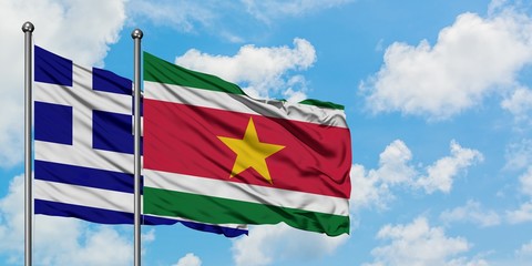 Greece and Suriname flag waving in the wind against white cloudy blue sky together. Diplomacy concept, international relations.