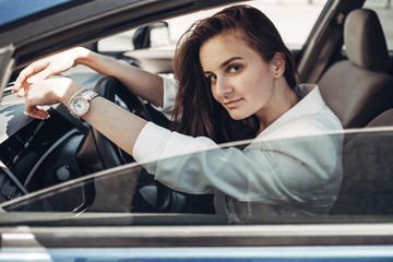 Fototapeta na wymiar Fashion Stylish Driver Girl in White Suit Sitting in the Car