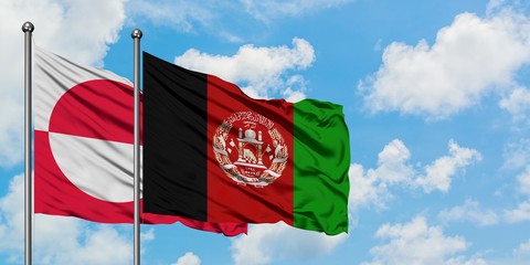 Greenland and Afghanistan flag waving in the wind against white cloudy blue sky together. Diplomacy...