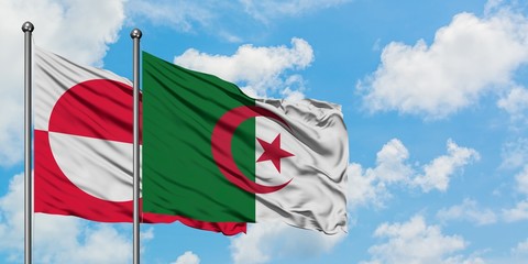 Greenland and Algeria flag waving in the wind against white cloudy blue sky together. Diplomacy...