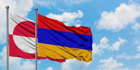 Greenland and Armenia flag waving in the wind against white cloudy blue sky together. Diplomacy...