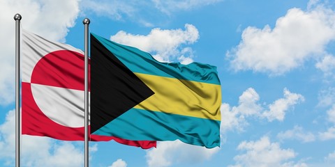 Greenland and Bahamas flag waving in the wind against white cloudy blue sky together. Diplomacy concept, international relations.