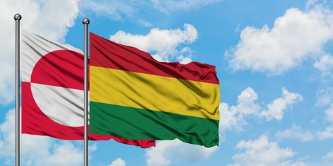 Greenland and Bolivia flag waving in the wind against white cloudy blue sky together. Diplomacy concept, international relations.