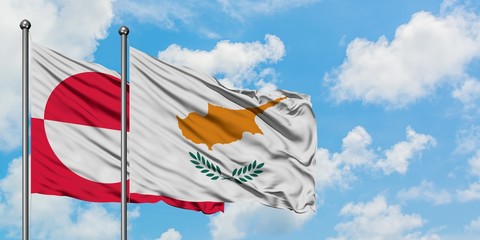 Greenland and Cyprus flag waving in the wind against white cloudy blue sky together. Diplomacy...