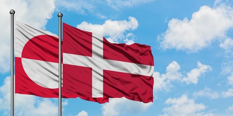 Greenland and Denmark flag waving in the wind against white cloudy blue sky together. Diplomacy concept, international relations.