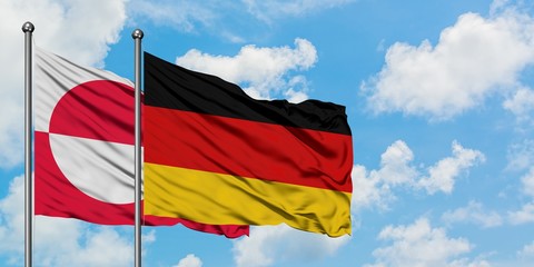 Greenland and Germany flag waving in the wind against white cloudy blue sky together. Diplomacy concept, international relations.