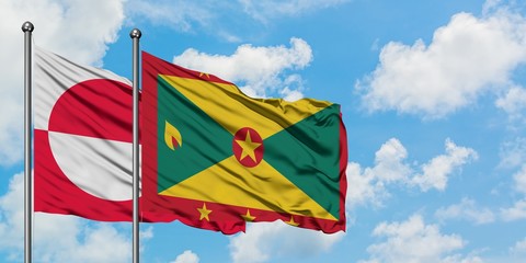 Greenland and Grenada flag waving in the wind against white cloudy blue sky together. Diplomacy concept, international relations.