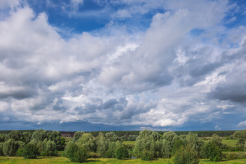 Amazing countryside landscape. Green valley, forests and blue sky with beautiful white fluffy clouds. Horizontal color photography.