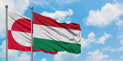 Greenland and Hungary flag waving in the wind against white cloudy blue sky together. Diplomacy concept, international relations.