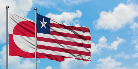 Greenland and Liberia flag waving in the wind against white cloudy blue sky together. Diplomacy concept, international relations.