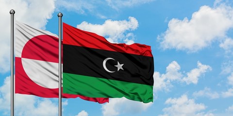 Greenland and Libya flag waving in the wind against white cloudy blue sky together. Diplomacy...