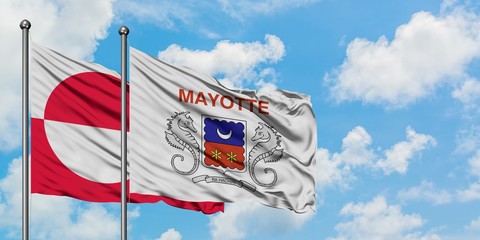 Greenland and Mayotte flag waving in the wind against white cloudy blue sky together. Diplomacy concept, international relations.