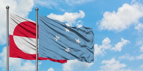 Greenland and Micronesia flag waving in the wind against white cloudy blue sky together. Diplomacy...