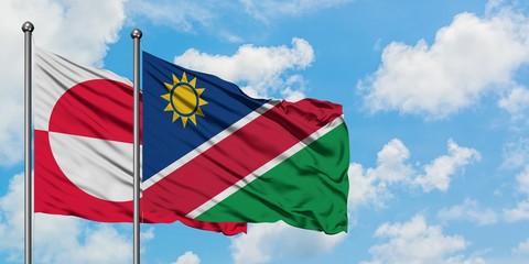 Greenland and Namibia flag waving in the wind against white cloudy blue sky together. Diplomacy concept, international relations.