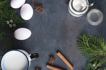 Fresh ingredients for cooking egg nog for Christmas day.Fresh eggs, milk, cinnamon, sugar, spices and fir branches as a decoration.Empty space for text